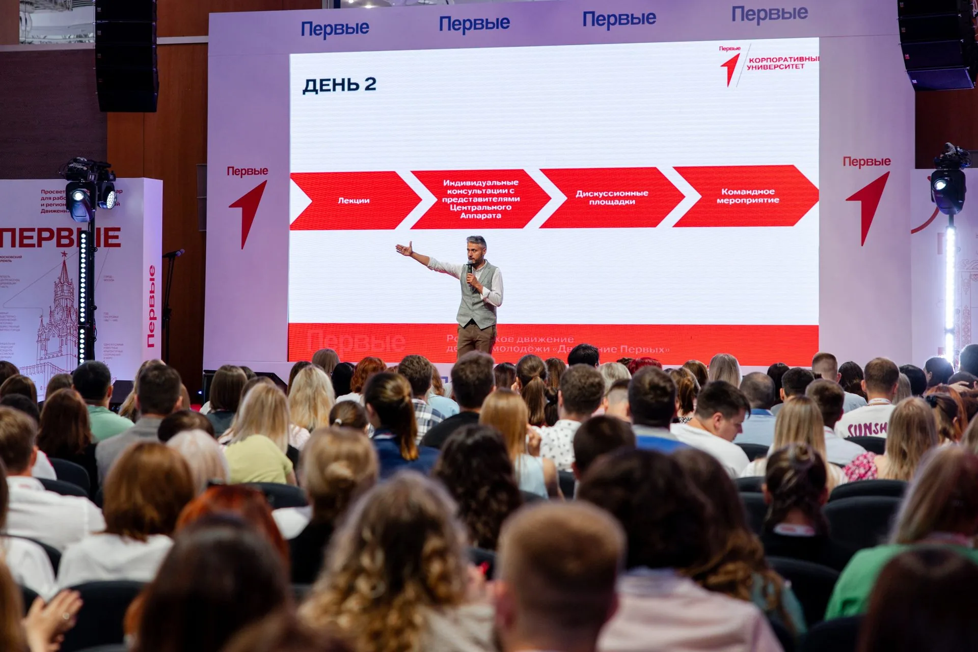 Спикер на сцене конференции перед LED-экраном, линейные массивы по краям портала